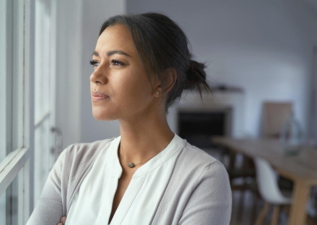 Woman gazing out a window, looking thoughtful