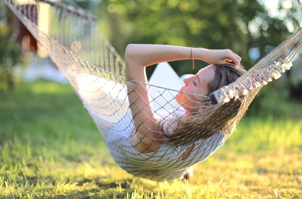 Woman resting peacefully in a hammock outdoors, representing nervous system rest after betrayal trauma