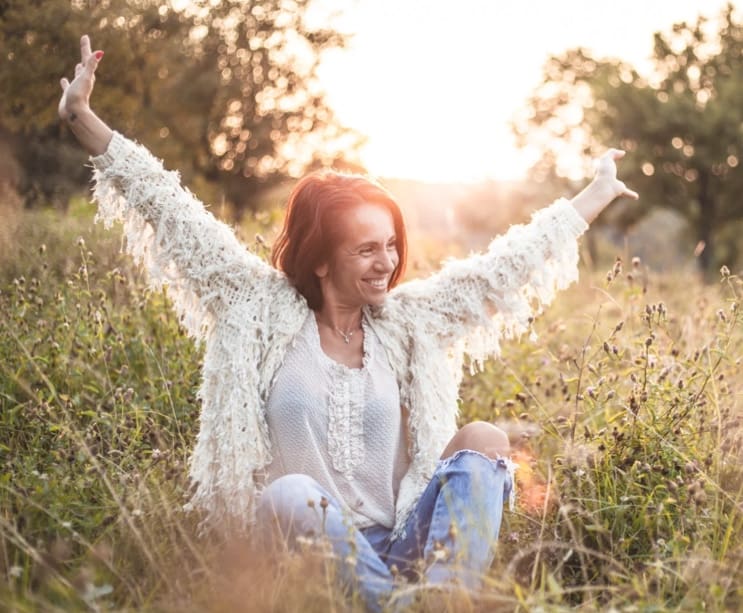 Woman raising her arms joyfully in a sunlit field, representing the lasting freedom clients experience through individual therapy at arKardia in Gettysburg, PA.