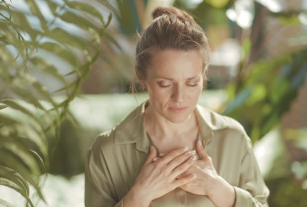 Woman with hands over her chest and eyes closed, reflecting the body-based processing used in EMDR and Brainspotting therapy.