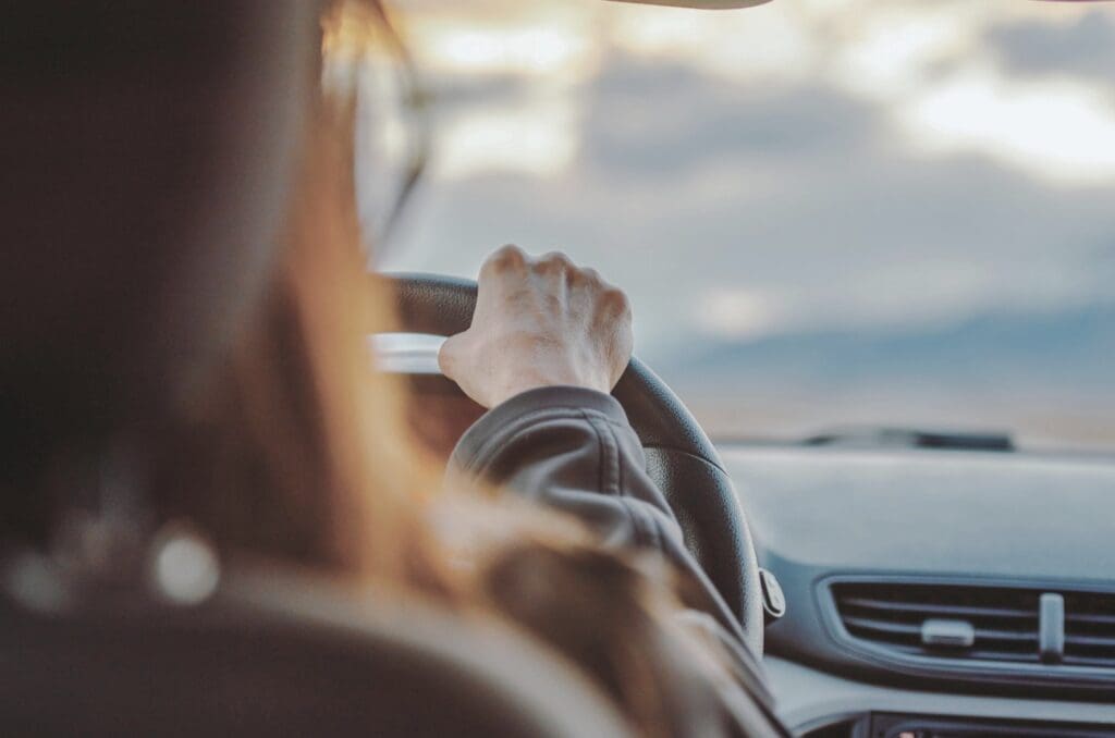 Woman sitting in her car with her hand on the steering wheel, not ready to go inside from divorce