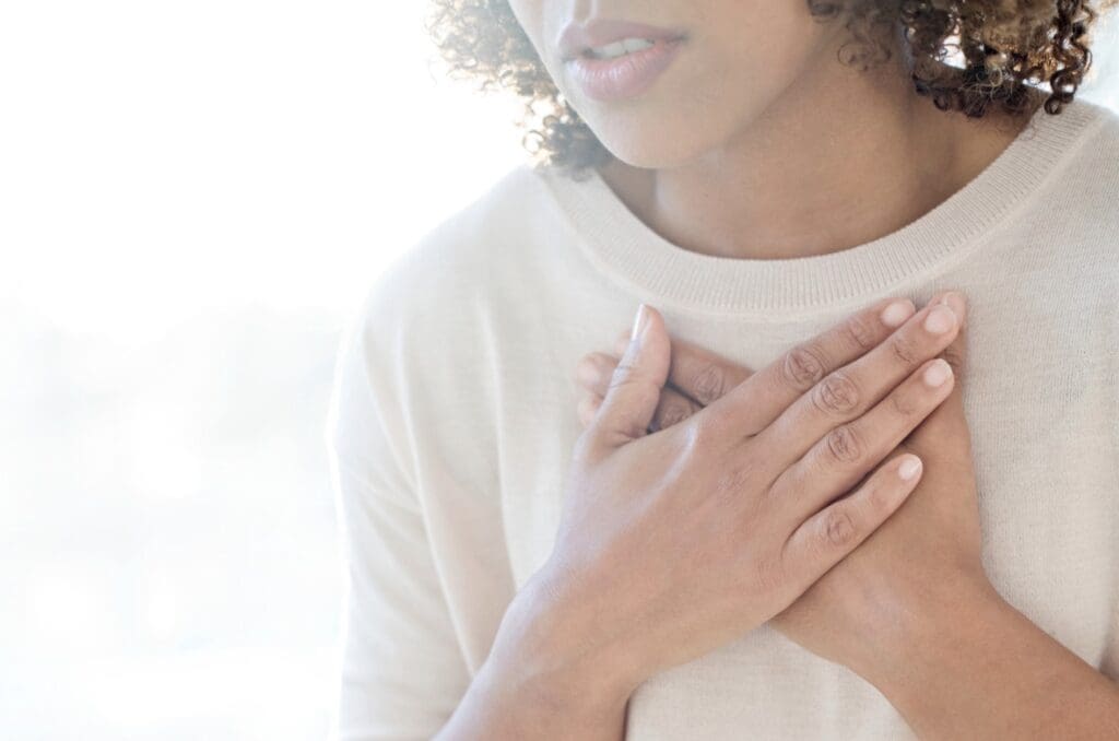 Woman with both hands crossed gently over her chest, Why do I doubt myself after being hurt